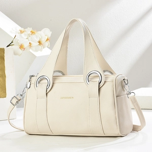 Elegant cream leather pillow bag with top handle and gold logo on minimalist background
