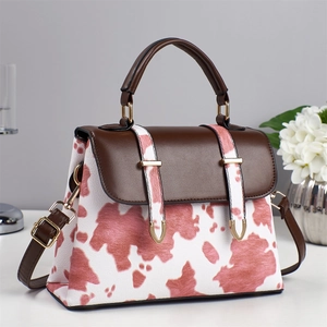 Crossbody handbag with pink cow print pattern and brown leather straps for daily styling