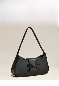 Detail of black faux leather underarm bag with vintage texture and 3D bow accent