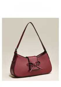 Macro detail of wine red crackle leather shoulder bag with decorative bow accent