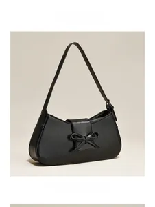 Close-up of black leather underarm bag featuring a bow detail and cracked vintage texture