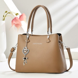 Détail du sac cabas en cuir marron avec breloque cœur et bandoulière amovible