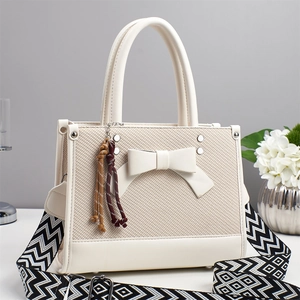 Détail du sac à main beige élégant avec nœud en tissu texturé et bandoulière tissée stylée
