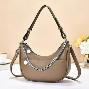 Khaki crescent shoulder bag with metallic chain and adjustable strap in cozy setting