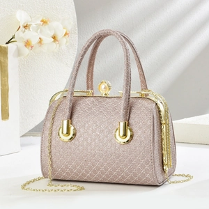 Sparkly champagne evening bag with pearl clasp and gold ring handle on a stone surface