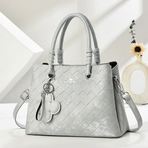Detail of metallic grey woven handbag with brand lettering and clover charm