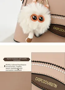 Détail du sac en cuir texturé avec broderie, logo doré et breloque chat en peluche