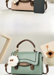 Détail d'un petit sac à main carré avec logo, pendentif en peluche et smartphone