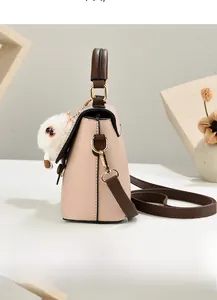 Vue latérale du sac à main en cuir rose avec poignée marron et pendentif de chat
