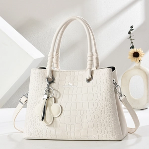 Detail of white crocodile pattern shoulder bag with handle, strap and floral charm