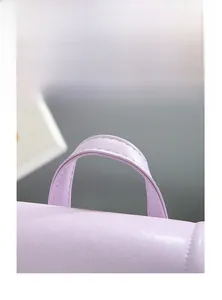 Macro detail of wide reinforced handle and soft synthetic leather texture on a purple bag