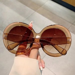 Close-up of oversized round amber tortoiseshell sunglasses with brown lenses for women