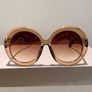 Detail of champagne oversized round sunglasses with gradient brown lenses and metal hinges