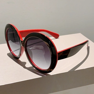 Detail view of round oversized sunglasses with black-red frame and gradient lenses