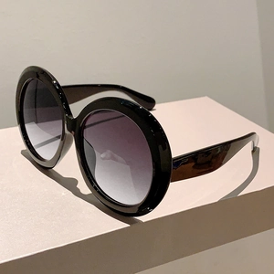 Detailed view of oversized round black sunglasses with gradient purple and grey lenses