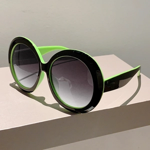 Macro detail of oversized round sunglasses with two-tone black and neon green frames