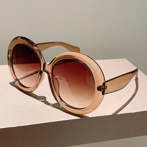 Detail view of round amber tortoiseshell sunglasses with brown gradient lenses