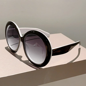 Detail of round oversized sunglasses with black and white frame and gradient lenses