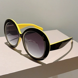 Detail of round oversized sunglasses featuring black and yellow dual-color contrast frame
