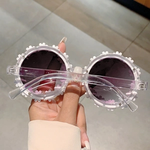 Detailed close-up of white daisy floral frame kids sunglasses with purple gradient lenses