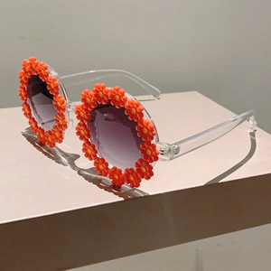 Detailed side view of children flower sunglasses with transparent frames and orange petals