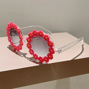 Detail of kids daisy flower sunglasses with transparent frame and pink floral trim