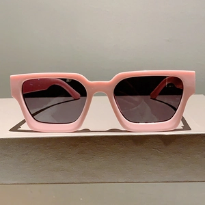 Vue détaillée des lunettes de soleil rectangulaires roses avec monture épaisse