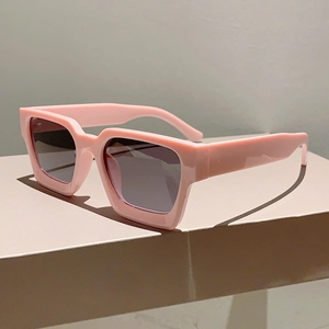 Vue latérale de lunettes de soleil carrées roses avec verres gris sur socle beige
