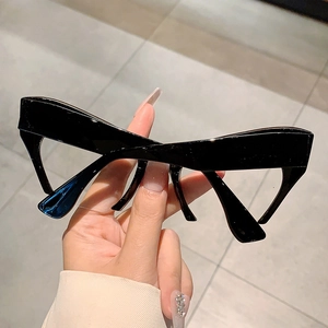 Macro view of glossy black thick-frame cat-eye glasses with retro bold-line design