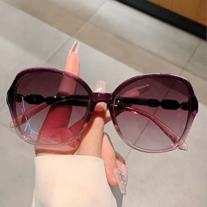 Close-up of stylish oversized sunglasses with purple gradient lenses and chain temple detail