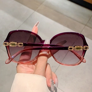 Detail view of purple gradient lenses and luxury gold chain temple on oversized sunglasses
