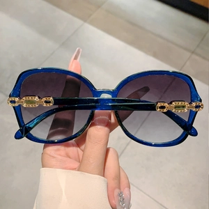 Close-up of luxury oversized sunglasses with gradient lenses and gold chain hinge detail