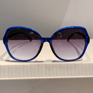 Front view of royal blue oversized cat-eye sunglasses with gradient purple lenses