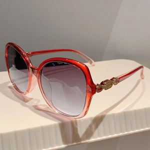 Detailed close-up of gradient red oversized sunglasses with golden chain metal temples