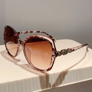 Detail of tortoise frame sunglasses with golden chain metal relief on the temple