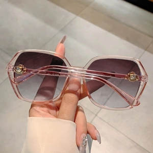 Detail of pink transparent frame sunglasses with golden crown emblem and gradient lenses
