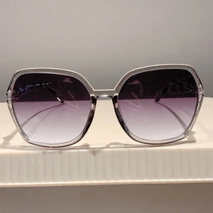 Close-up of oversized silver polygon sunglasses with purple gradient lenses
