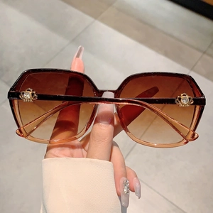 Detail of luxury sunglasses with gradient brown lenses and rhinestone crown hardware