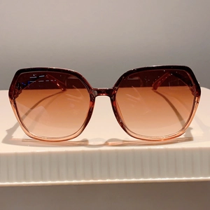 Detail of oversized sunglasses with brown gradient lenses and dark transparent frame