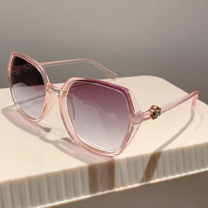 Close-up of pink transparent frame sunglasses with gradient lenses and gold metal accents