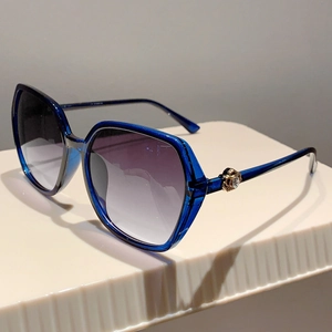 Detail of transparent blue oversized sunglasses with golden rhinestone crown accents