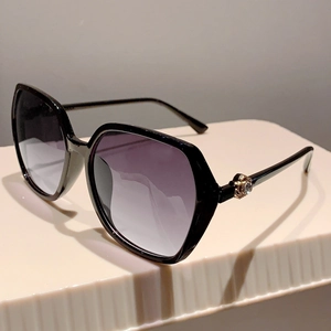 Detail of black hexagonal sunglasses featuring purple gradient lenses and gold rhinestones