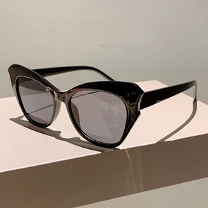 Close-up of black cat-eye sunglasses with thick frames and dark grey tinted lenses
