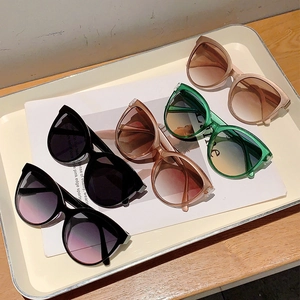 Five pairs of trendy oversized cat eye sunglasses in various candy colors on a magazine
