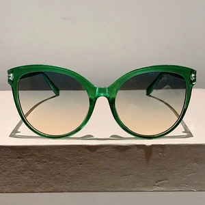 Detail view of cat eye sunglasses with green transparent frame and gradient lenses
