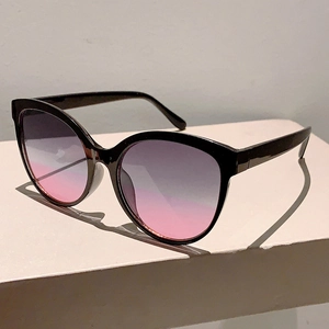 Detail of oversized black cat-eye sunglasses with purple to pink gradient lenses