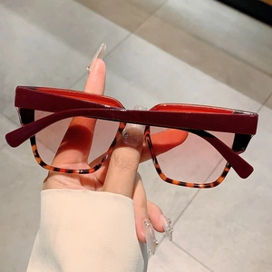 Detailed close-up of square oversized sunglasses with burgundy frame and tortoise shell lower trim