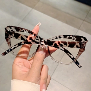 Detailed close-up of tortoise shell cat-eye glasses frame held by hand for style