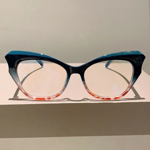 Detail of cat eye glasses frame featuring green to orange tortoiseshell gradient finish