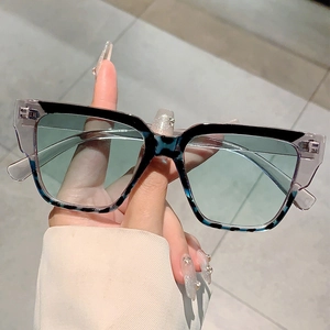 Detail of square oversized sunglasses with two-tone frame and light green lenses